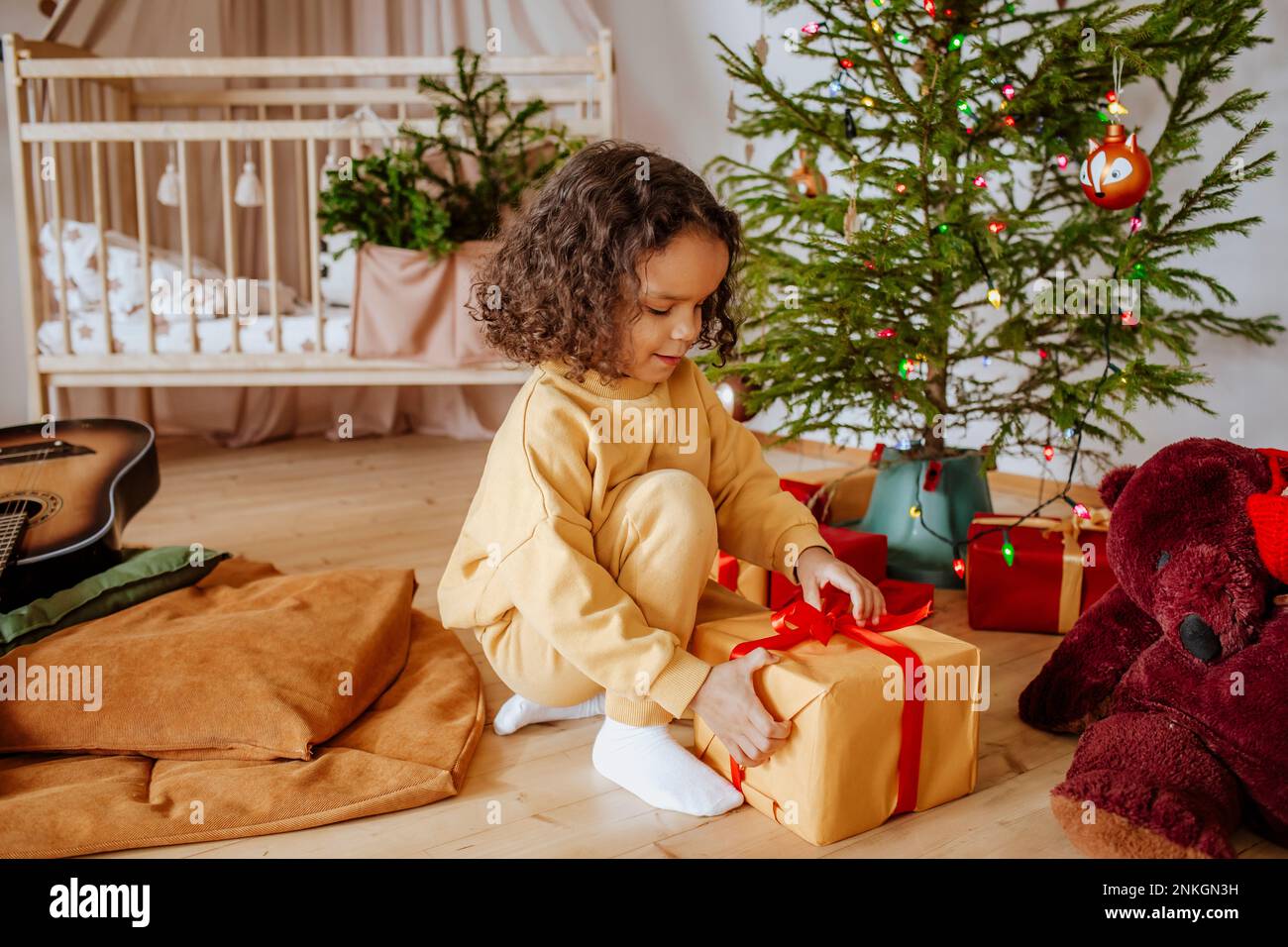 Cute girl opening gifts iunder Christmas tree at home Stock Photo