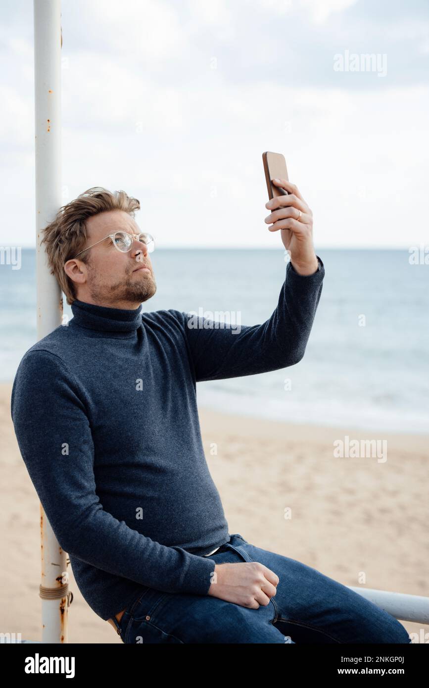 Man using mobile phone at beach Stock Photo