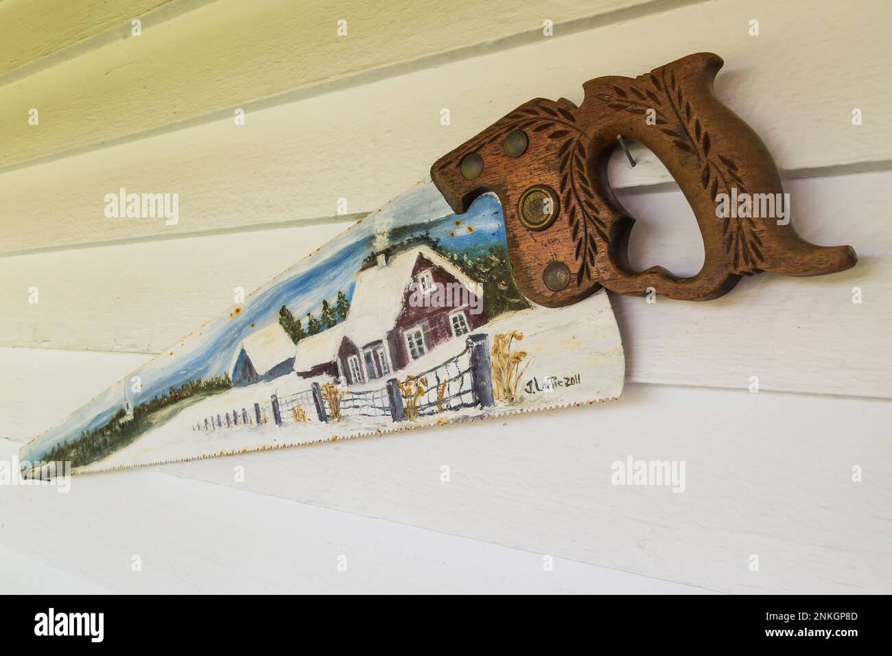 Antique wood cutting saw with carved details on handle and winter scene painted on blade