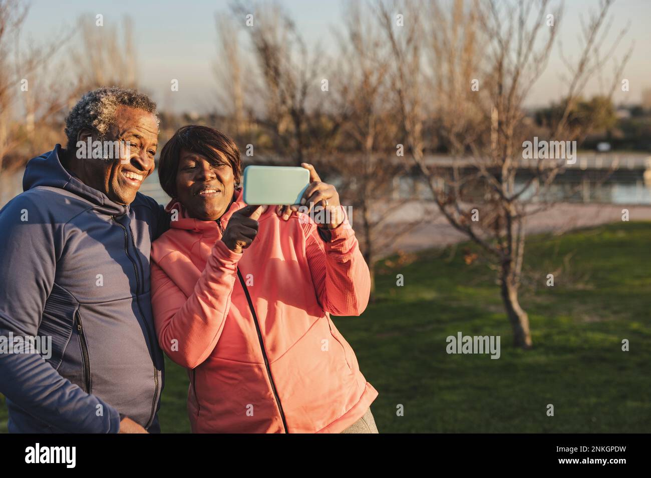 Happy senior woman sharing smart phone with man at park Stock Photo