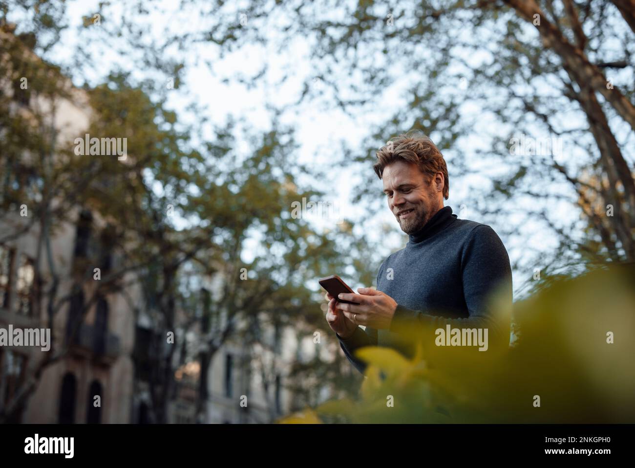 Smiling man using mobile phone Stock Photo