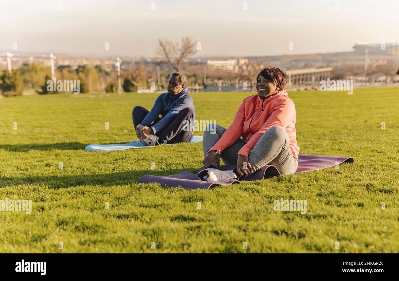 Senior couple doing yoga in park Stock Photo
