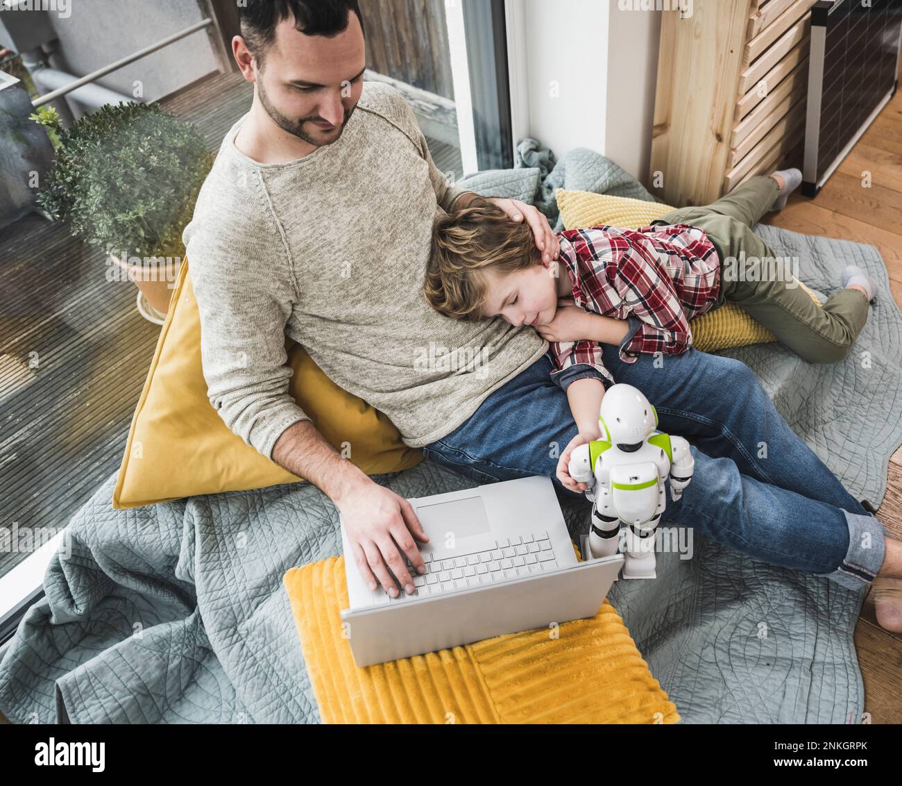 Son napping on father using laptop at home Stock Photo - Alamy