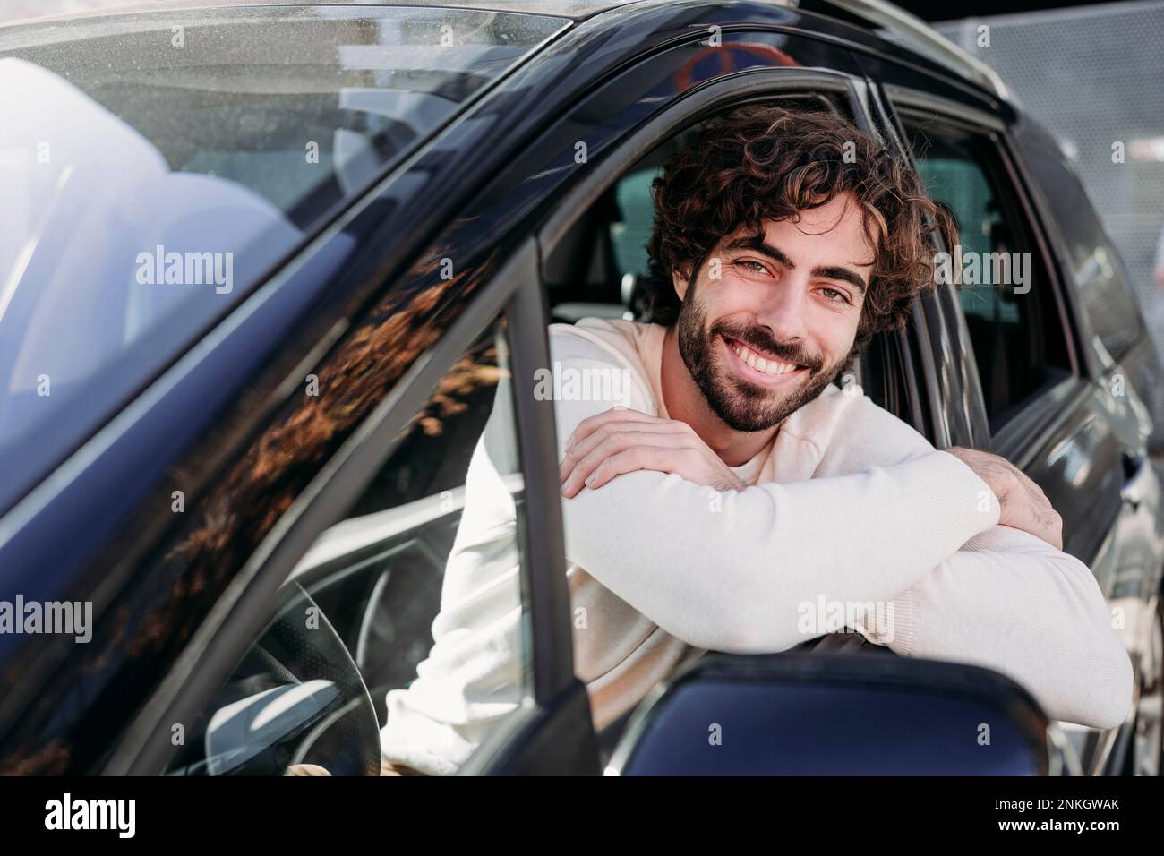Happy young man leaning on car window Stock Photo