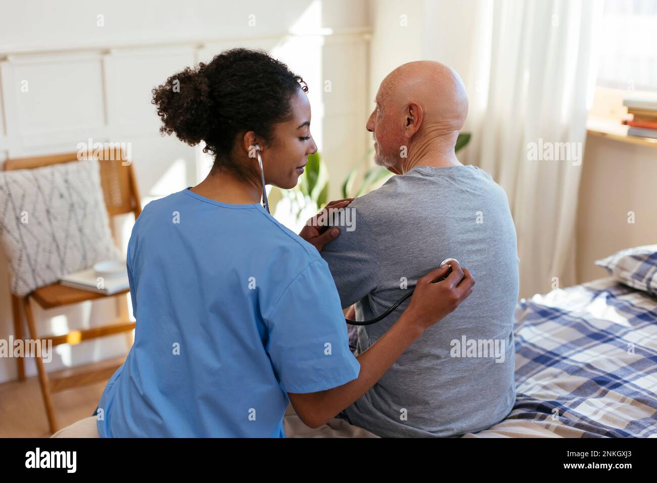 Doctor using stethoscope examining patient at home Stock Photo