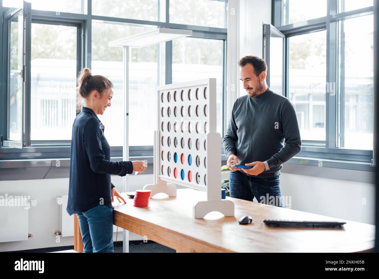 Business colleagues playing connect four dots game in office Stock Photo