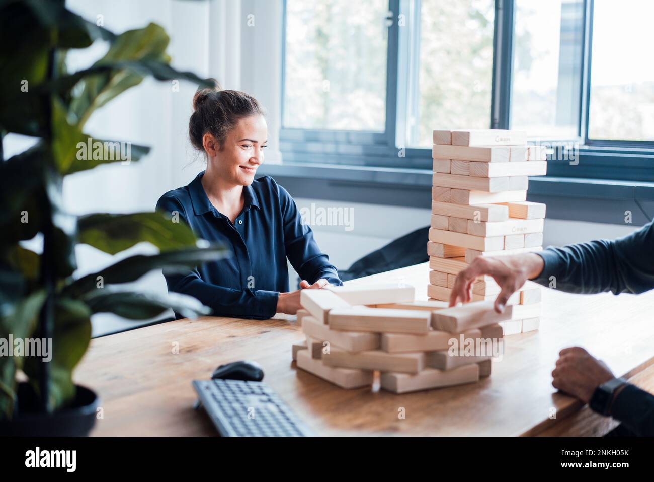 Business people stacking up wooden jenga blocks in office Stock Photo