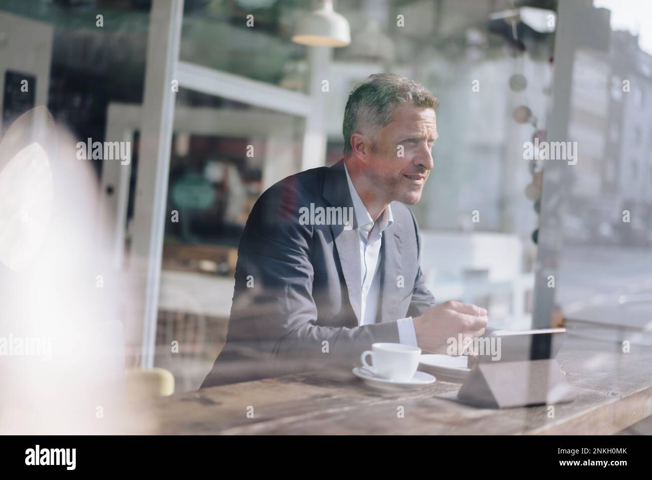 Mature businessman having breakfast seen through glass in cafe Stock Photo