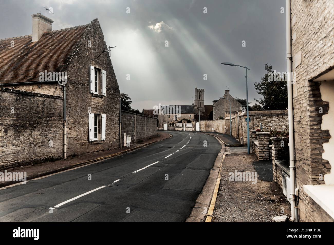 Sunlight streaming through clouds over empty street in old town Stock Photo