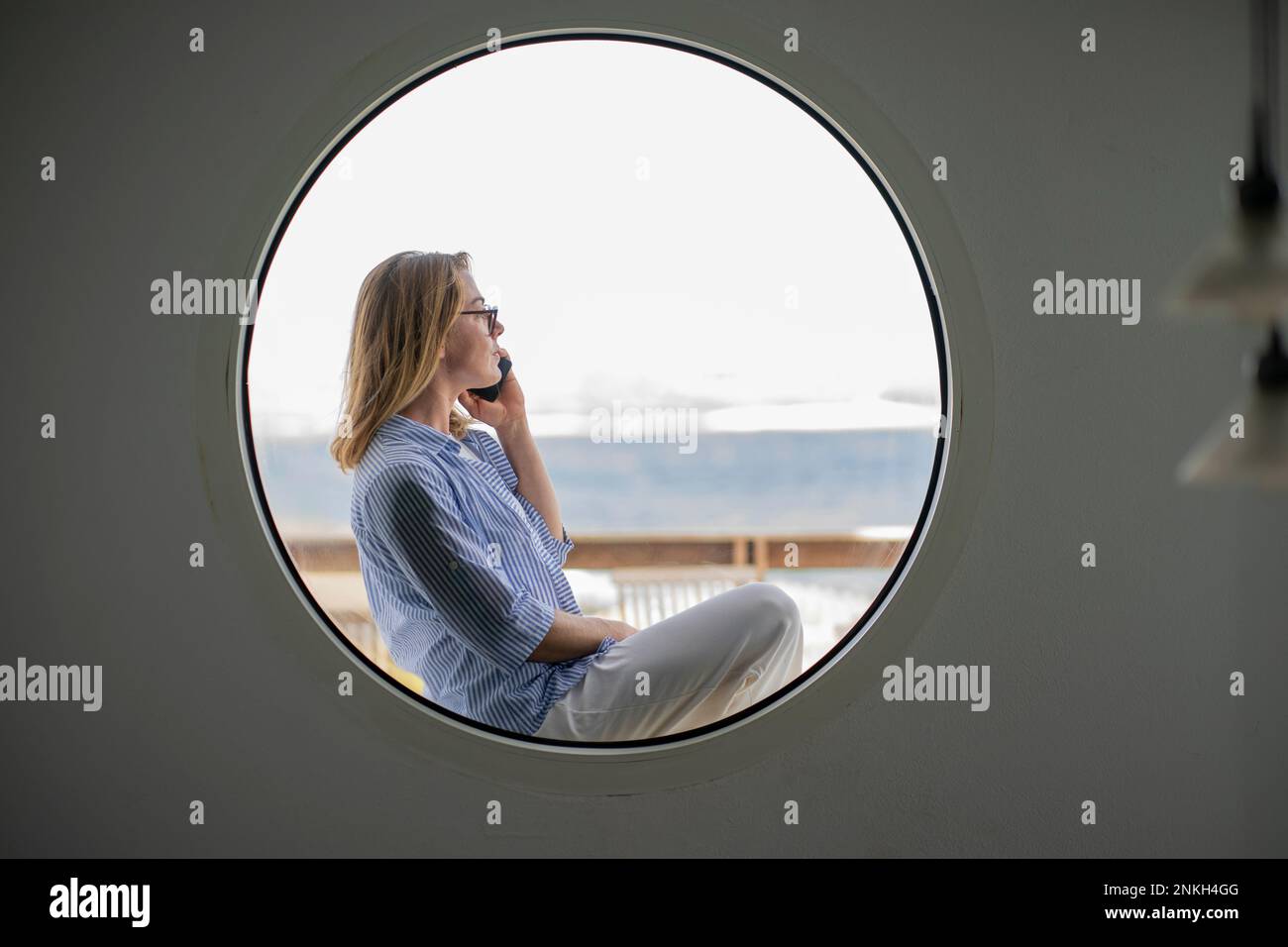 Businesswoman talking on smart phone seen through circle shaped window Stock Photo