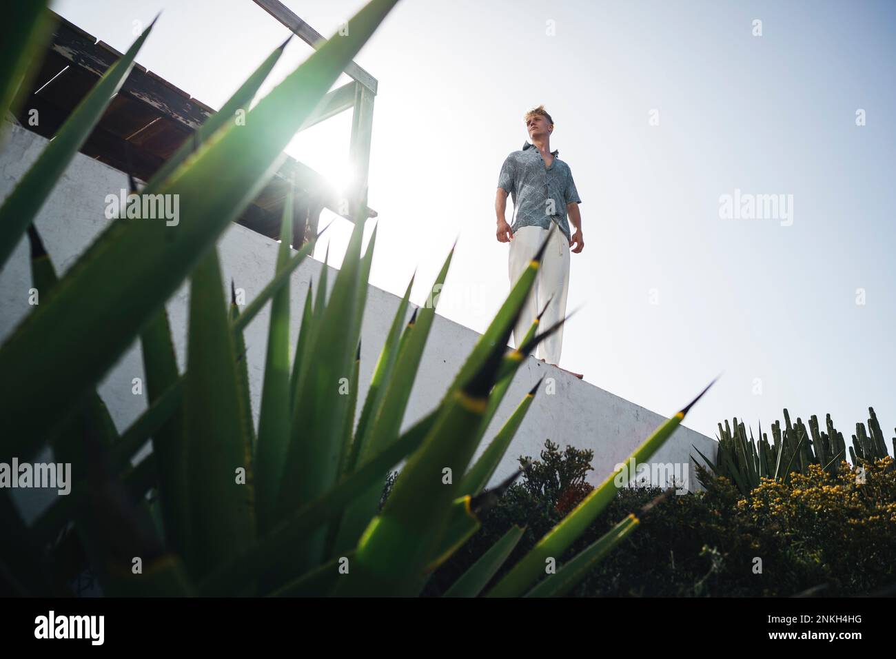 Young man standing on wall under bright sky Stock Photo