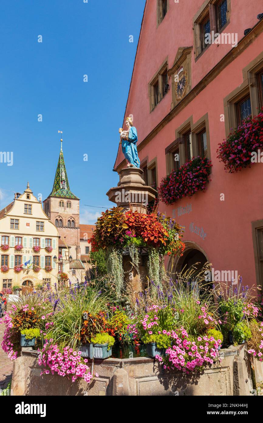 France, Grand Est, Turckheim, Figurine of virgin Mary on top of fountain covered in blooming flowers Stock Photo