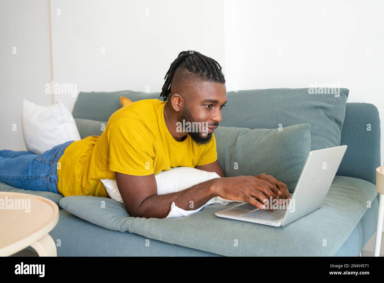 Freelancer lying on sofa and using laptop at home Stock Photo