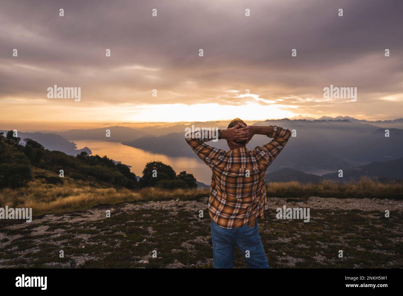 Mature man with hands behind head standing on mountain Stock Photo