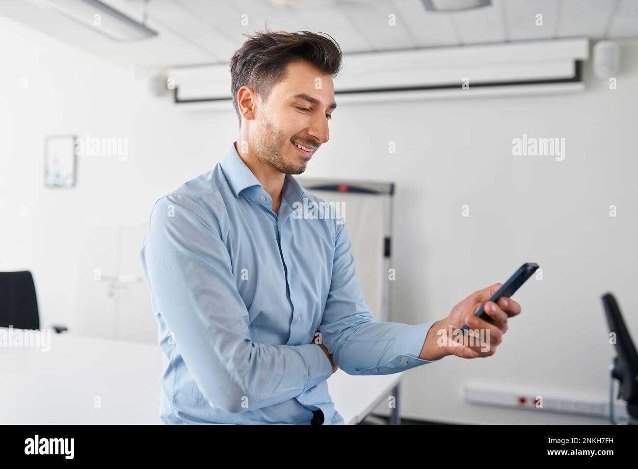 Smiling businessman using mobile phone at workplace Stock Photo