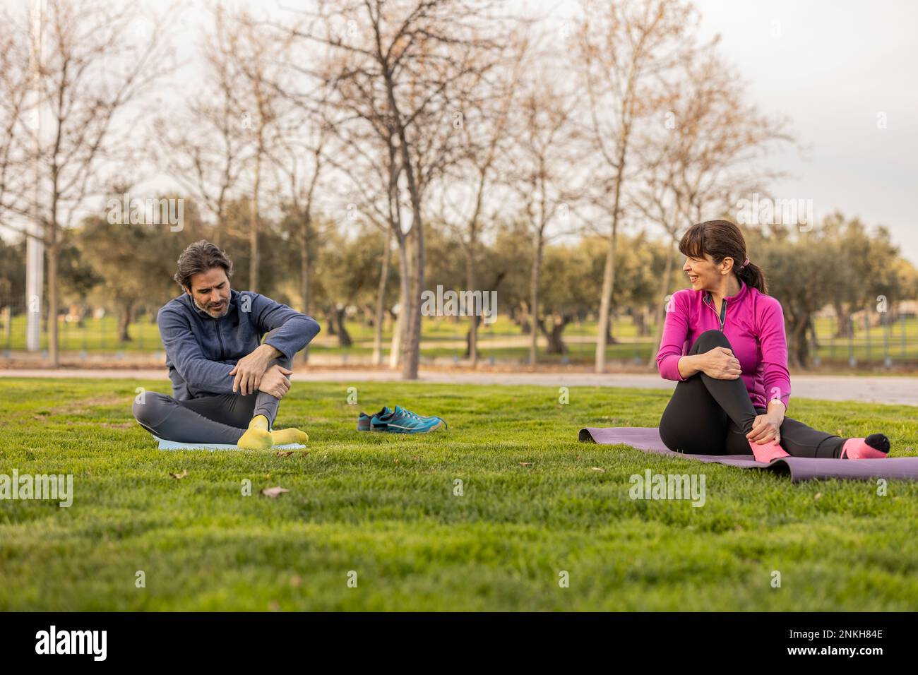 Happy mature couple practicing yoga in park Stock Photo