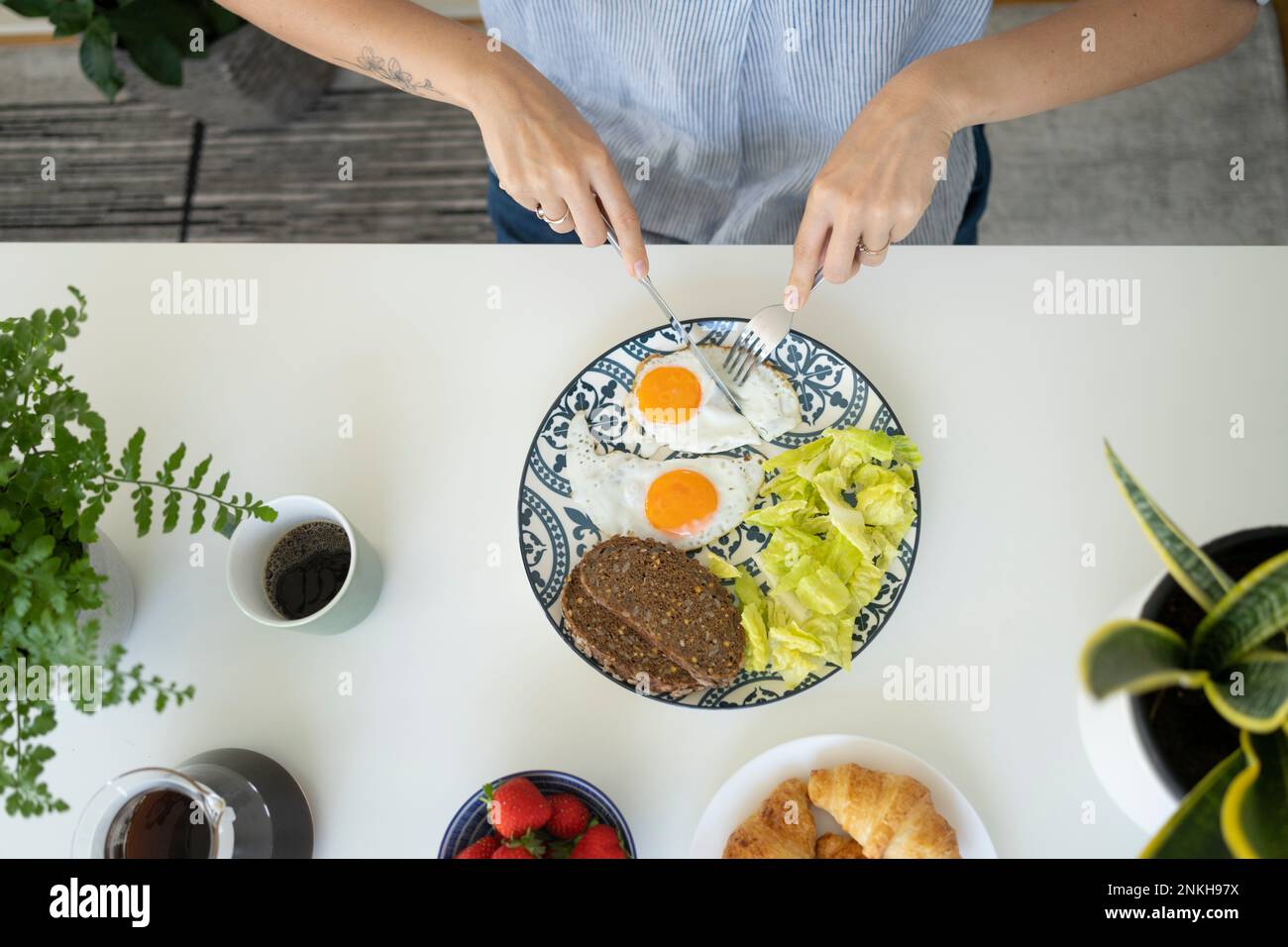 Woman having breakfast at table Stock Photo