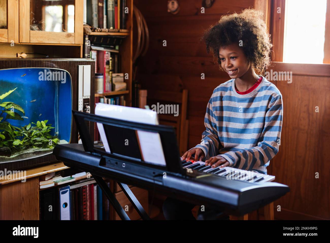 Smiling boy practicing electric piano at home Stock Photo