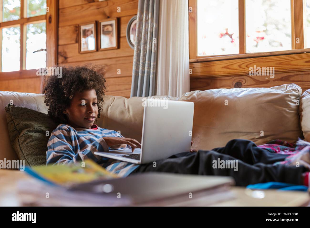 Boy using laptop resting on sofa at home Stock Photo