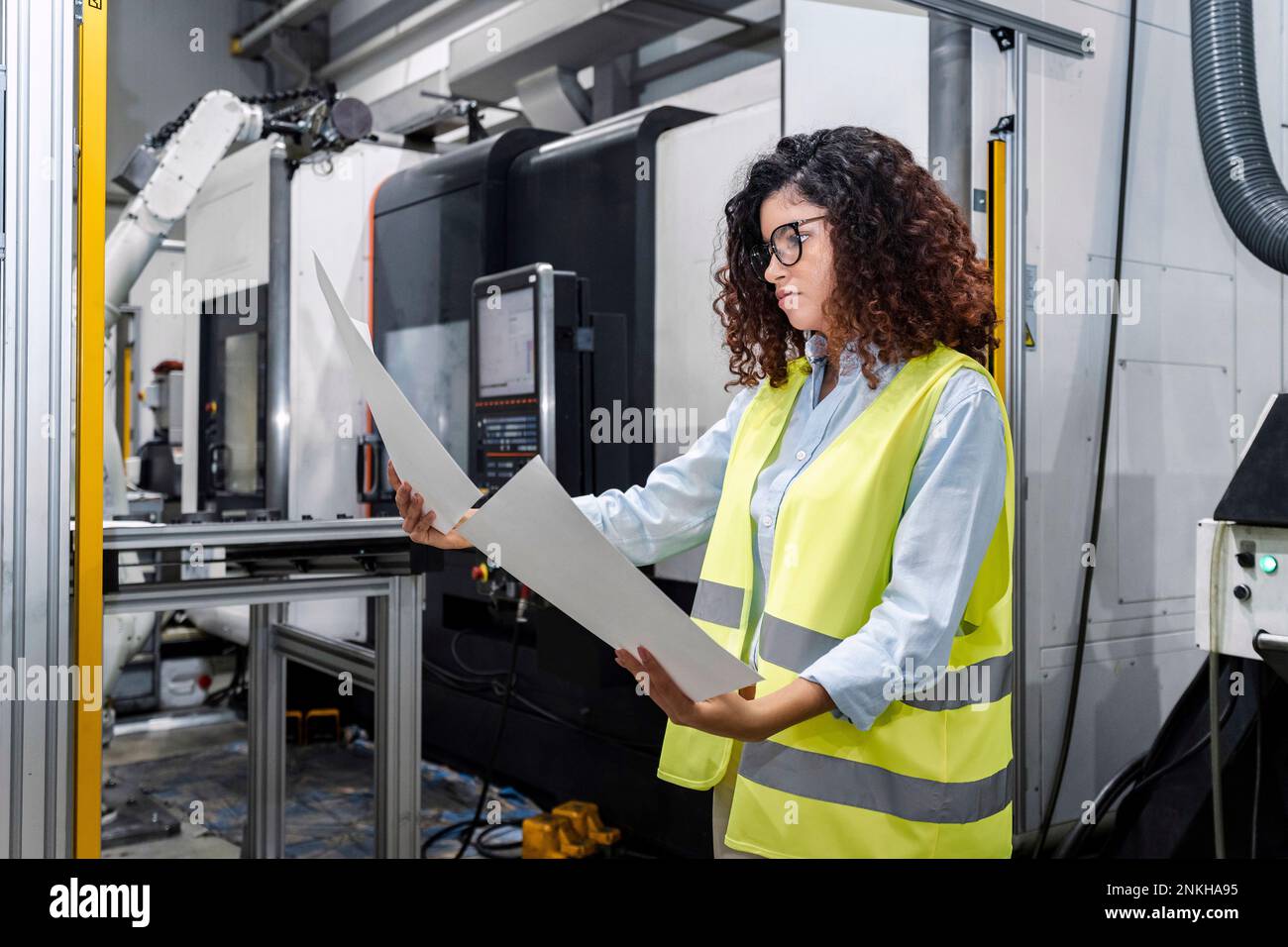 Young engineer examining blueprints standing by machine in industry Stock Photo