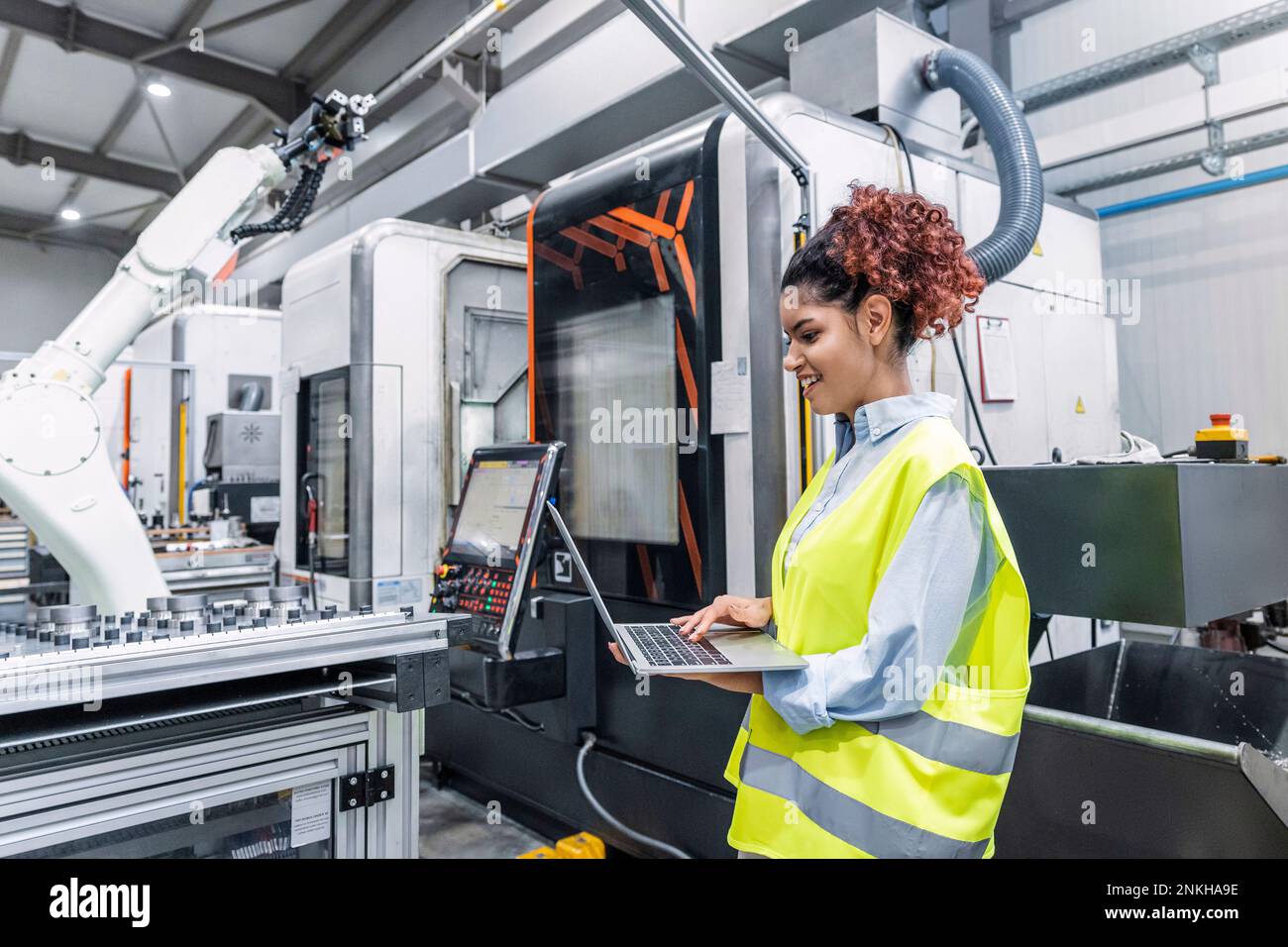 Happy engineer using laptop in factory Stock Photo