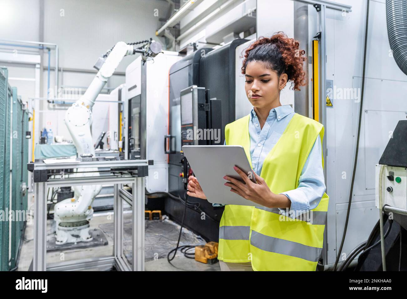 Engineer using tablet PC by machine in factory Stock Photo