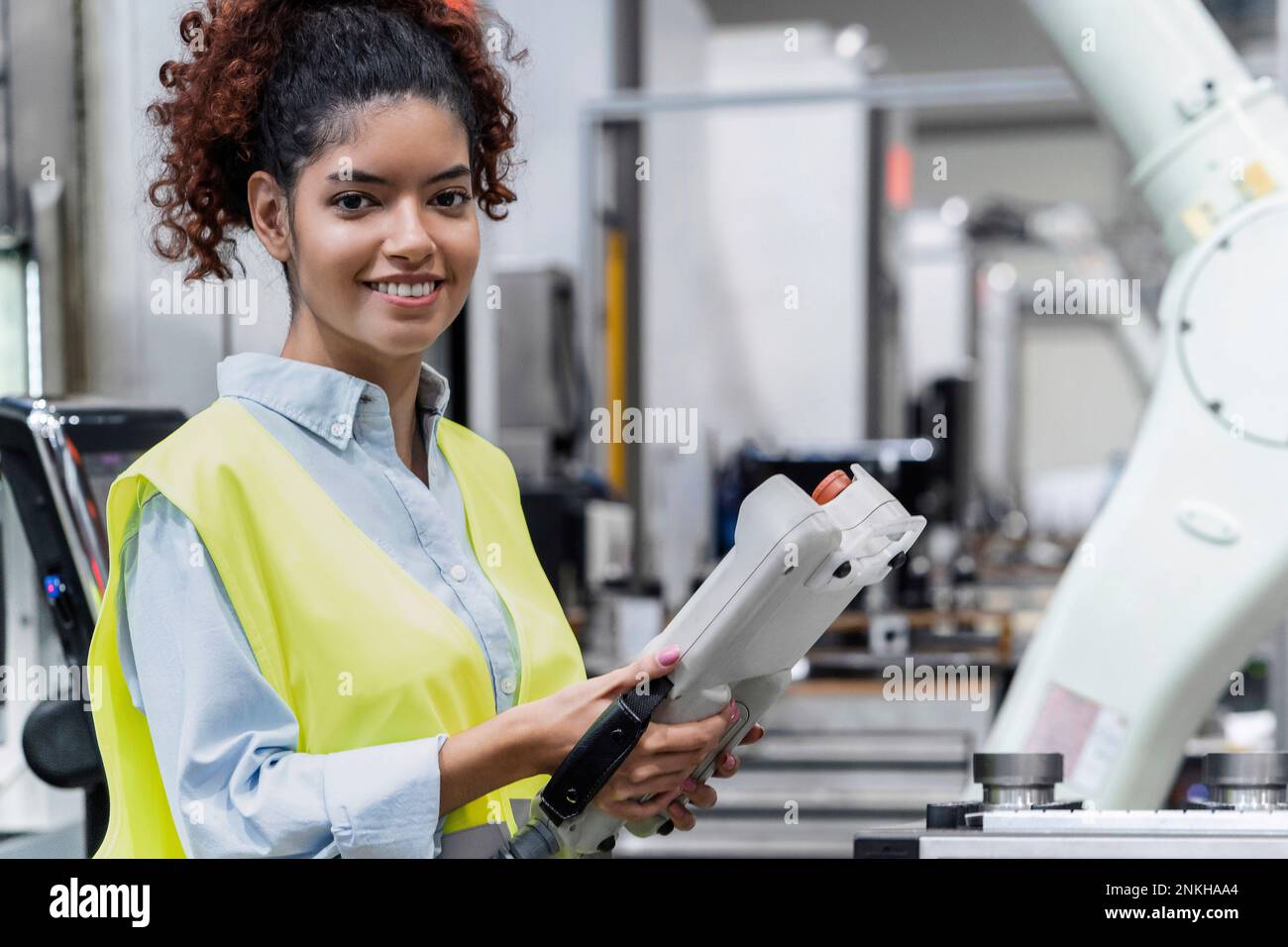 Smiling engineer standing with remote control in industry Stock Photo