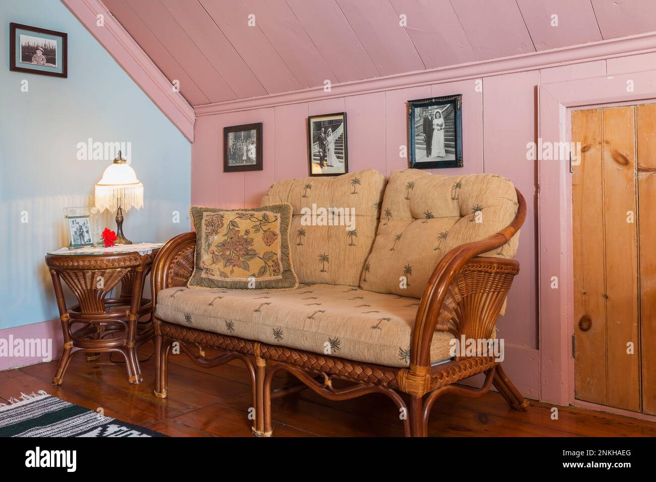 Rattan wicker sofa and end table in parlour room on upstairs floor inside old circa 1840 house. Stock Photo