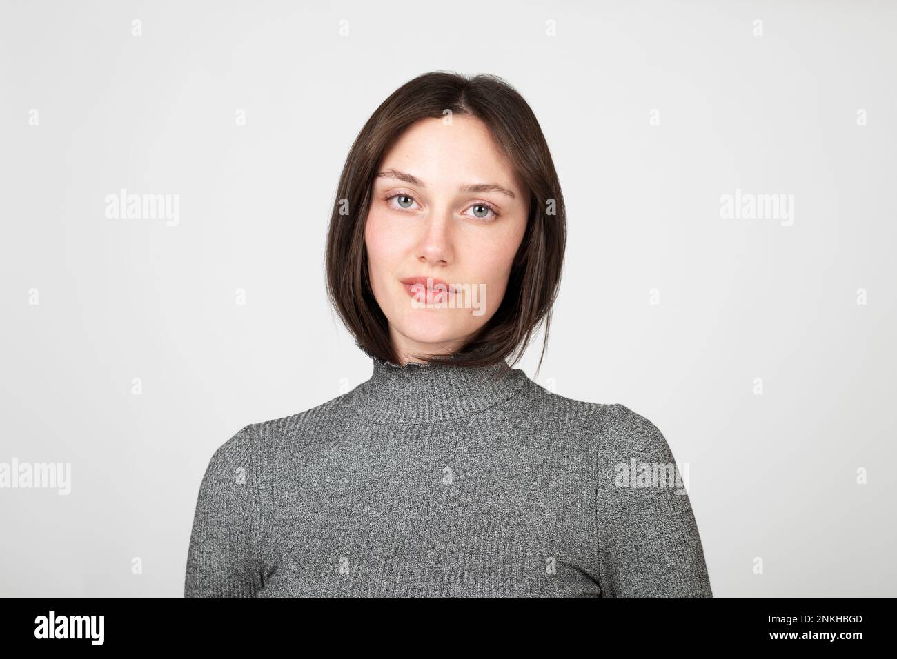 Confident young woman wearing turtleneck against white background Stock ...