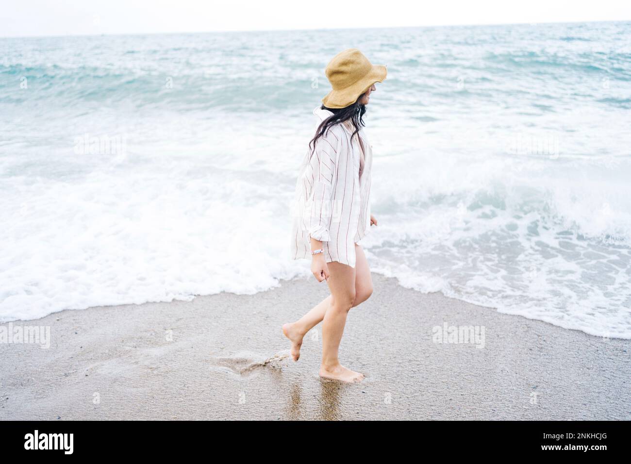 Woman wearing sun hat walking at beach Stock Photo - Alamy