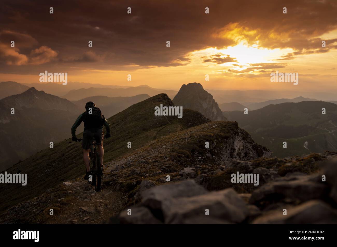 Man cycling on mountain at sunset Stock Photo