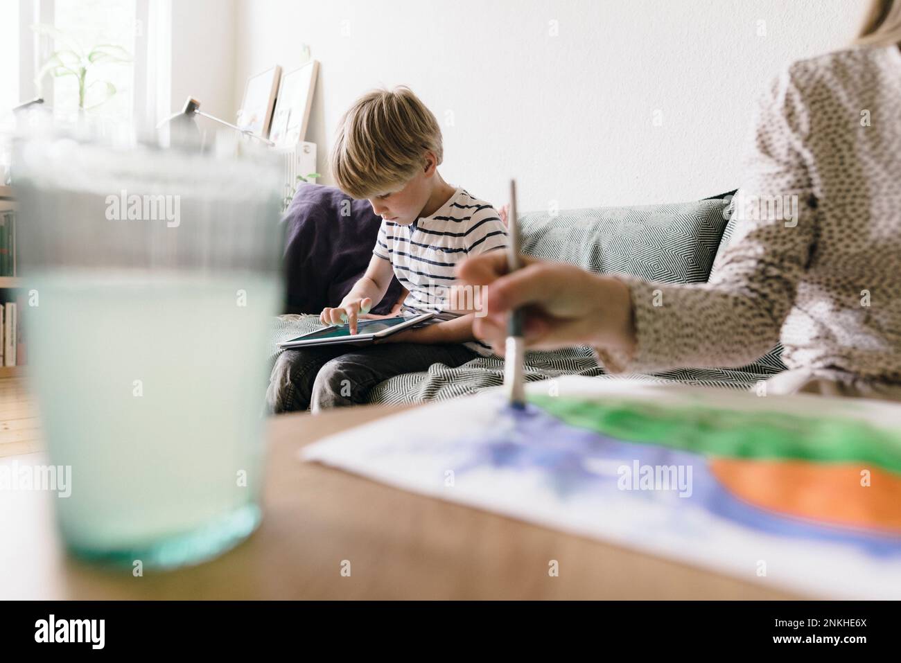 Boy using tablet PC sitting on sofa at home Stock Photo
