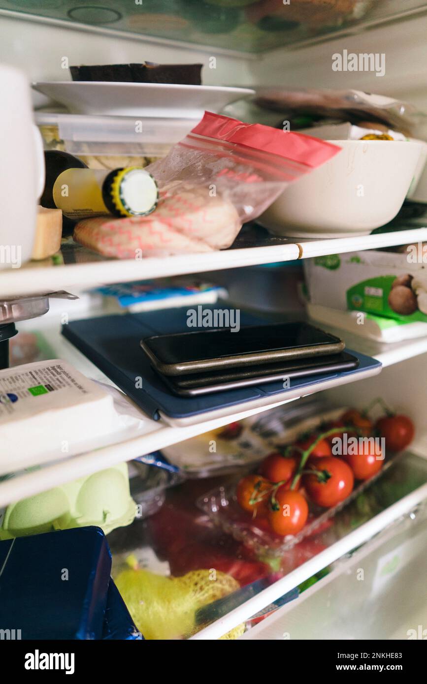 Smart phone and tablet PC with food stacked on shelf in refrigerator Stock Photo