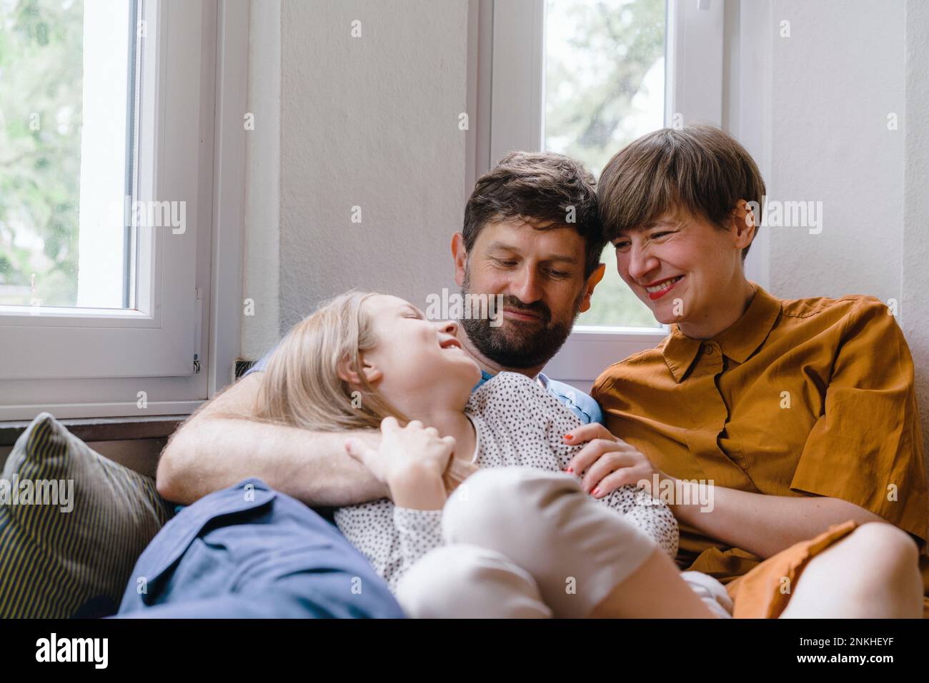 Father and mother spending leisure time with daughter at home Stock Photo