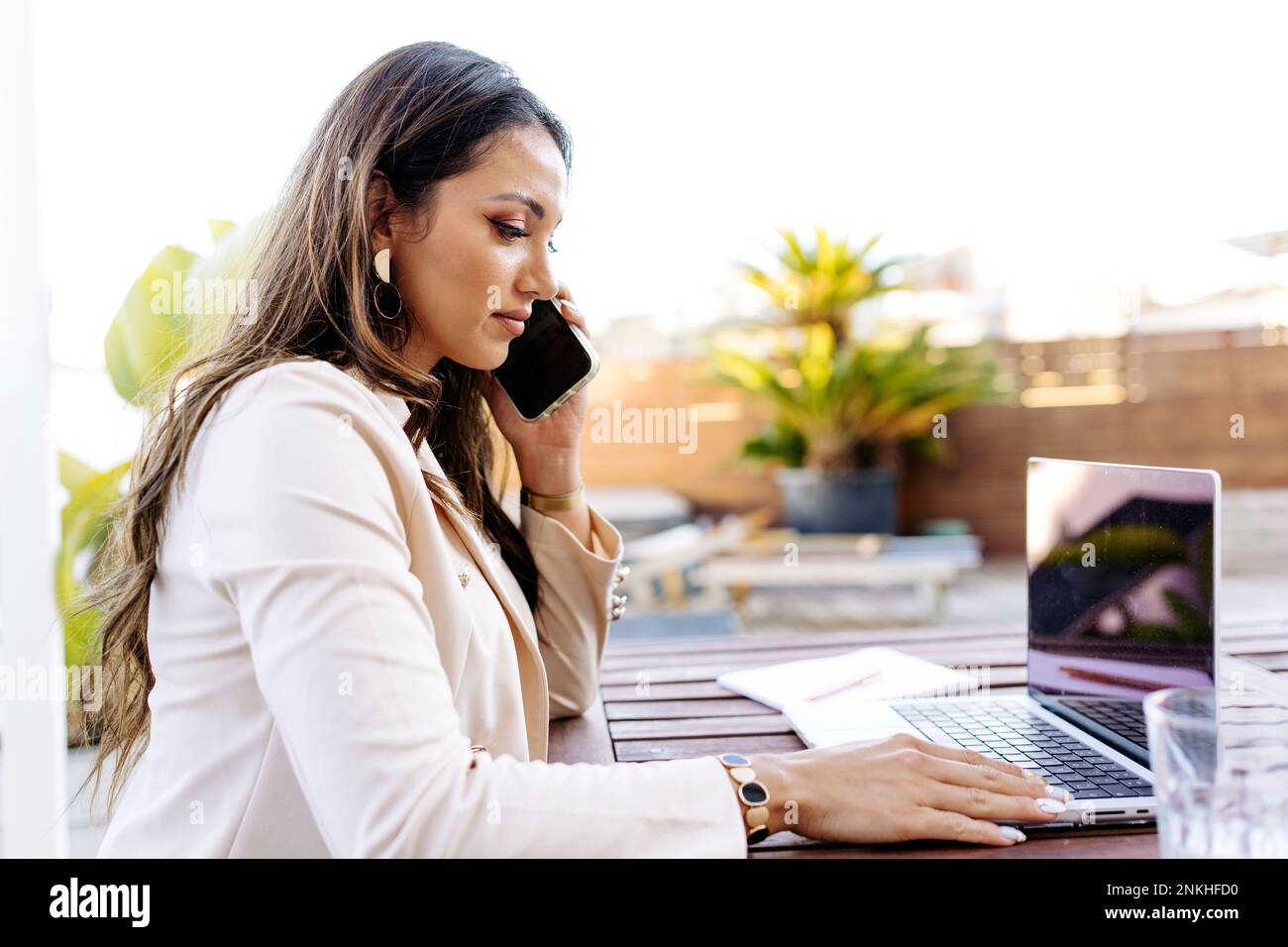 Freelancer talking on smart phone and using laptop Stock Photo