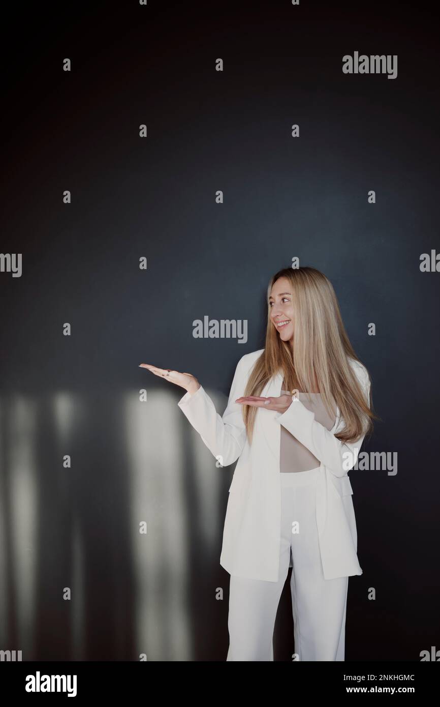 Smiling woman gesturing while standing in front of black wall Stock ...