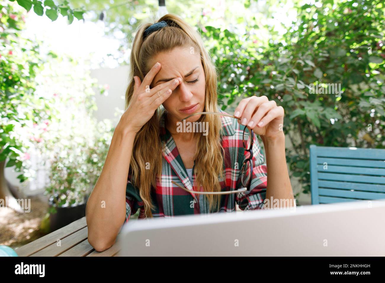 Tired freelancer rubbing eye at table in back yard Stock Photo