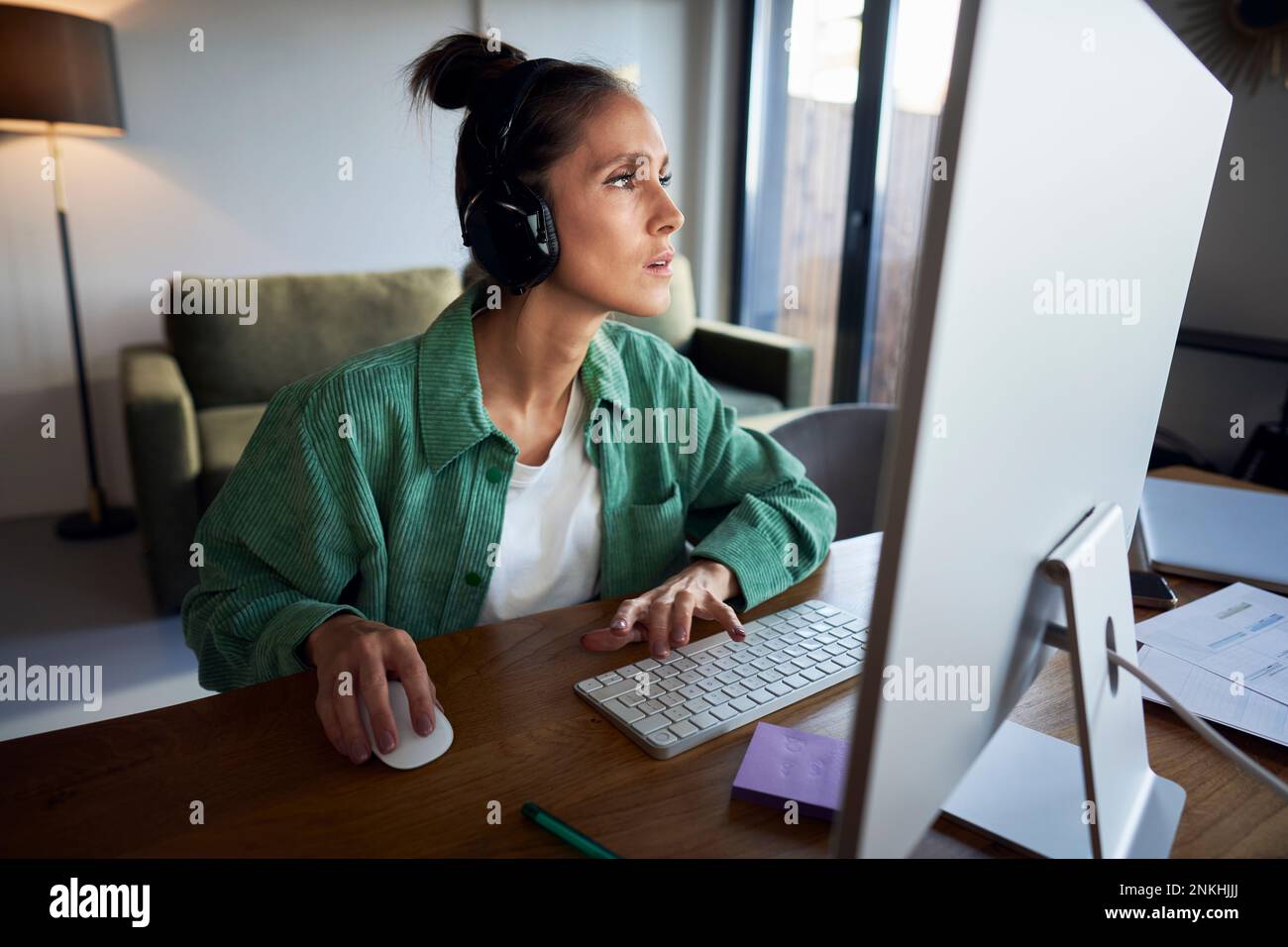 Freelancer wearing wireless headphones working on desktop PC Stock