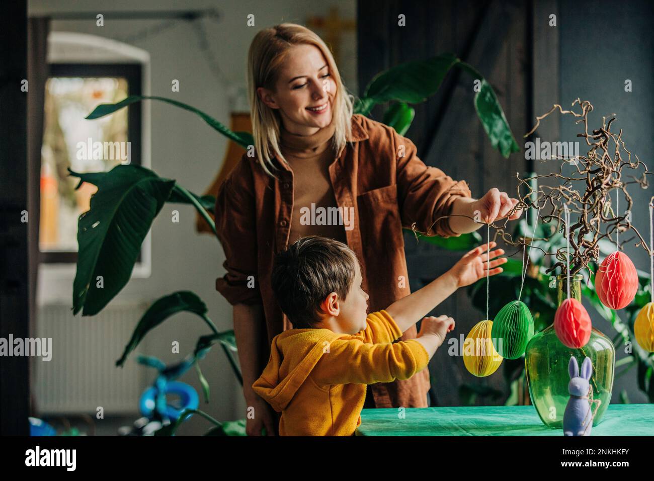 Happy mother and son decorating table for Easter dinner at home Stock Photo