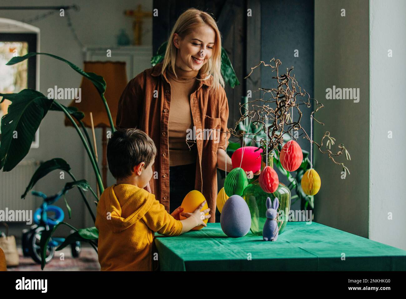 Smiling mother and son decorating table for Easter dinner at home Stock Photo