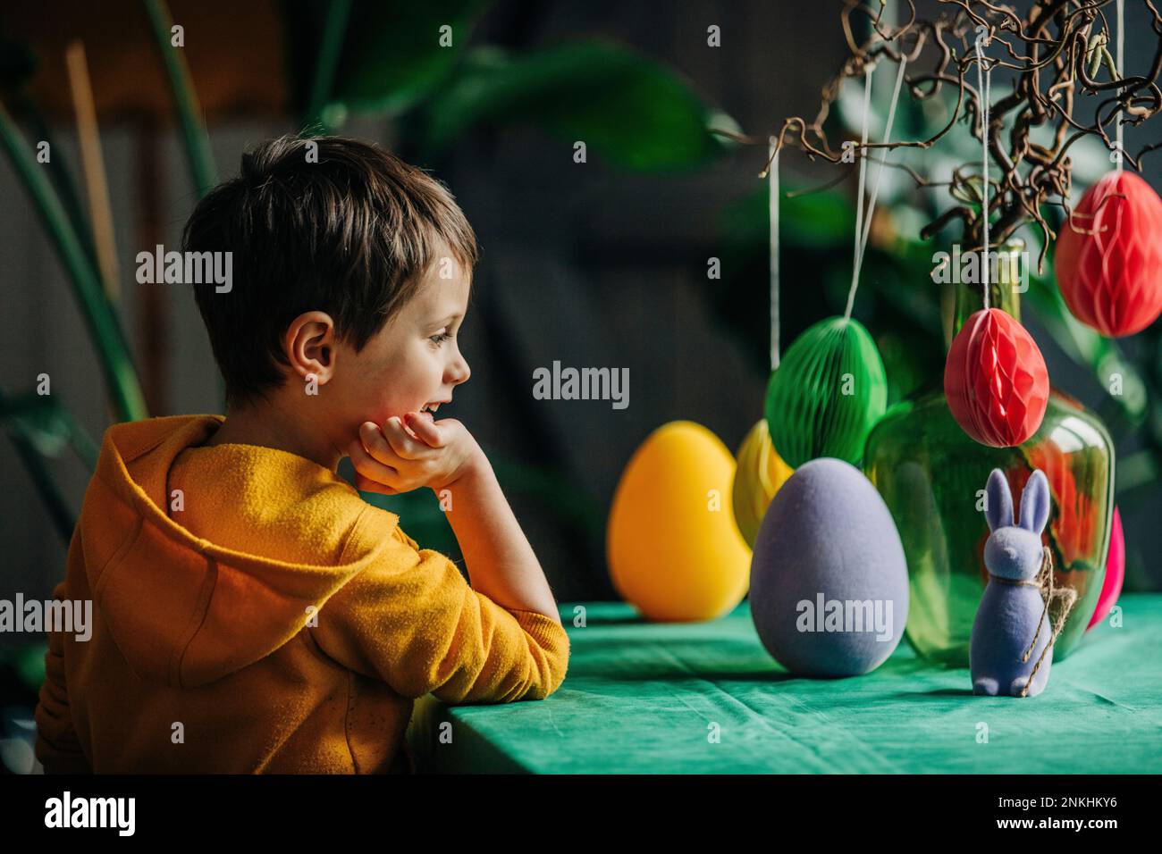 Smiling boy looking at Easter decoration on table at home Stock Photo