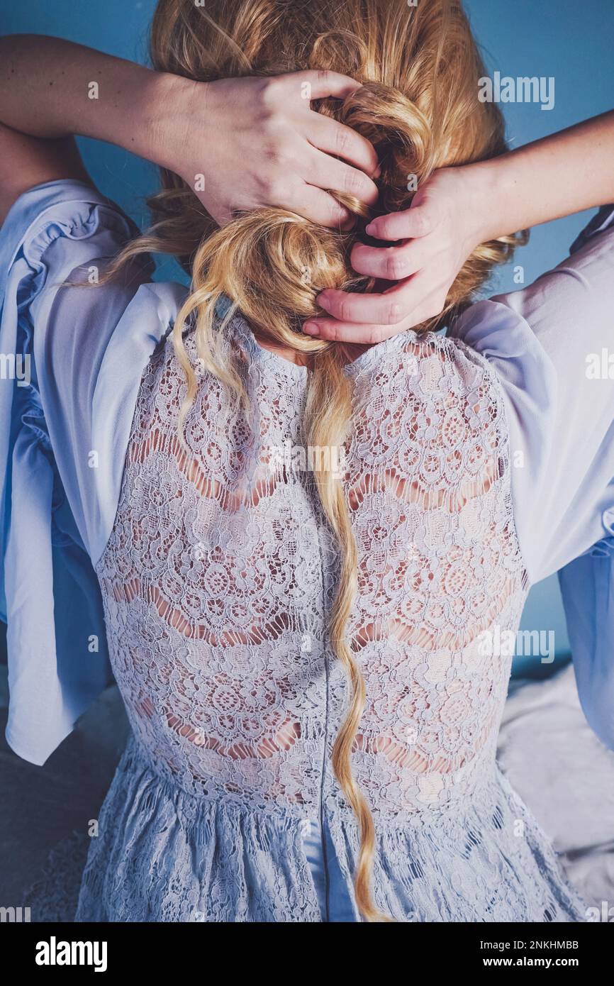 Woman wearing wedding dress tying hair bun Stock Photo Alamy