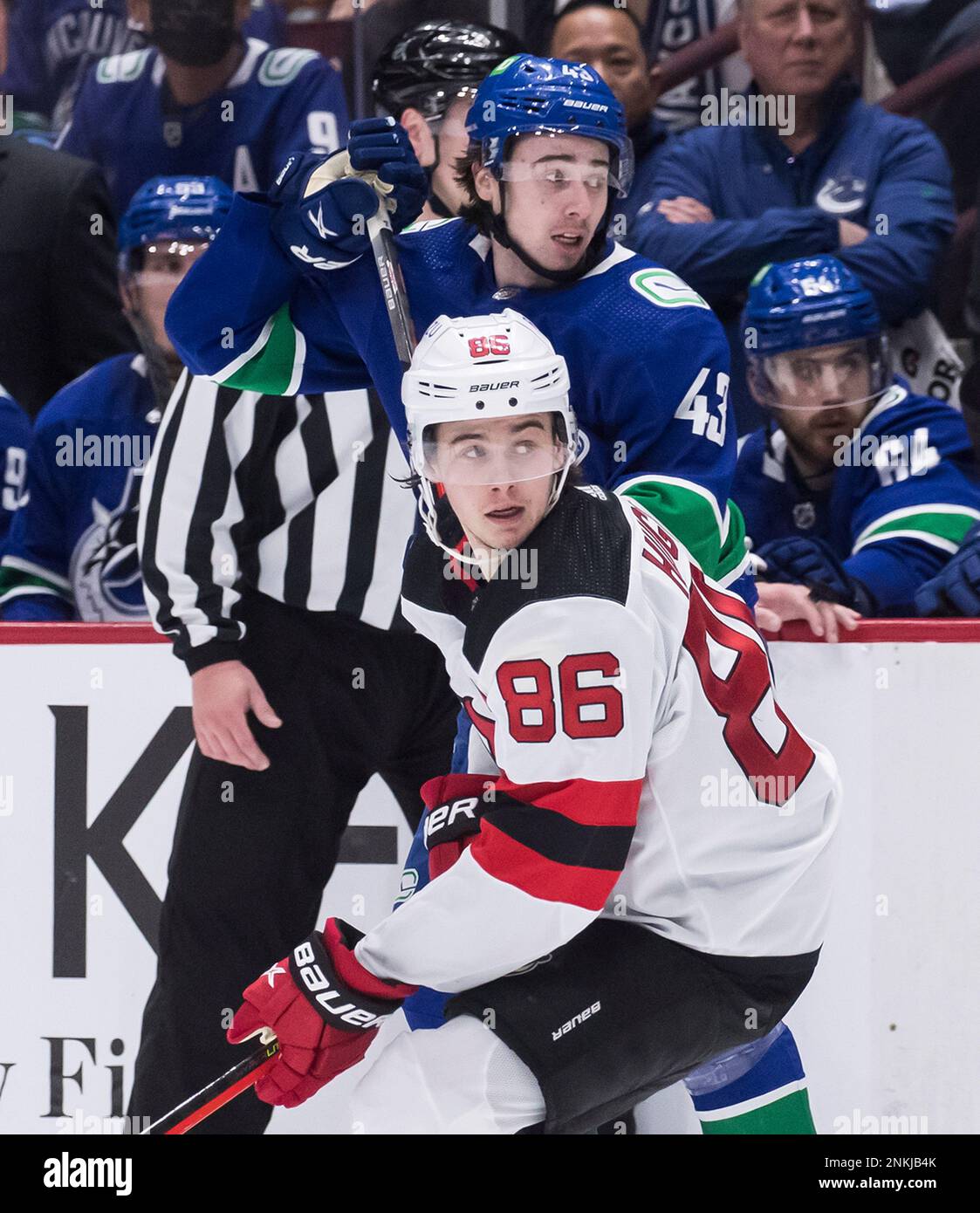 New Jersey Devils Jack Hughes, front, and his brother, Vancouver Canucks Quinn Hughes, watch a play during the second period of an NHL hockey game Tuesday, March 15, 2022, in Vancouver, British
