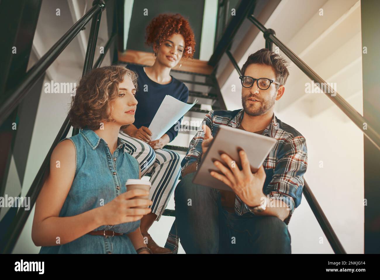 Where focus goes, energy flows. creative employees having a discussion on the staircase at work. Stock Photo