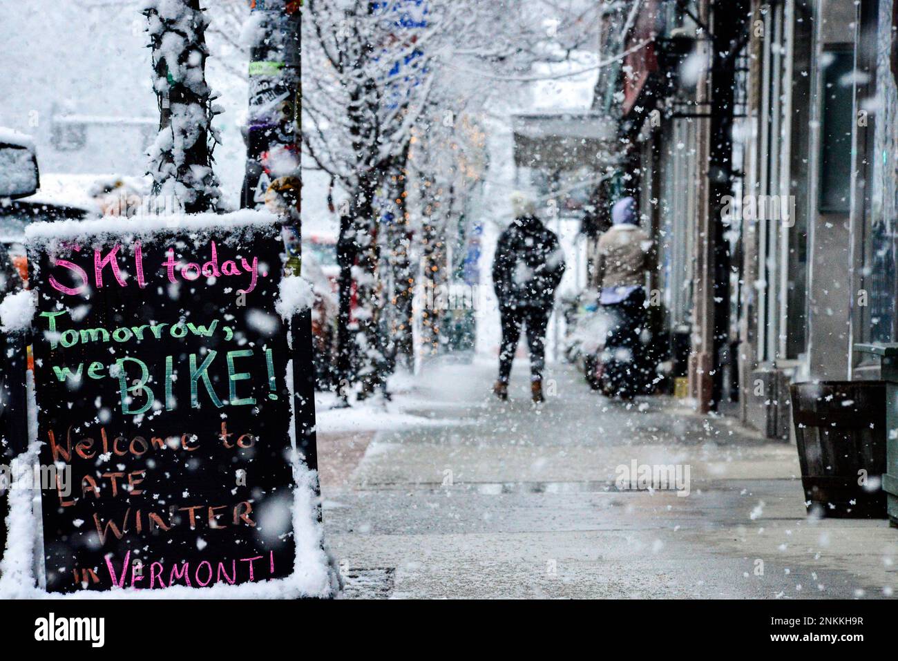 People walk along Main Street as snow falls in Brattleboro, Vt., on