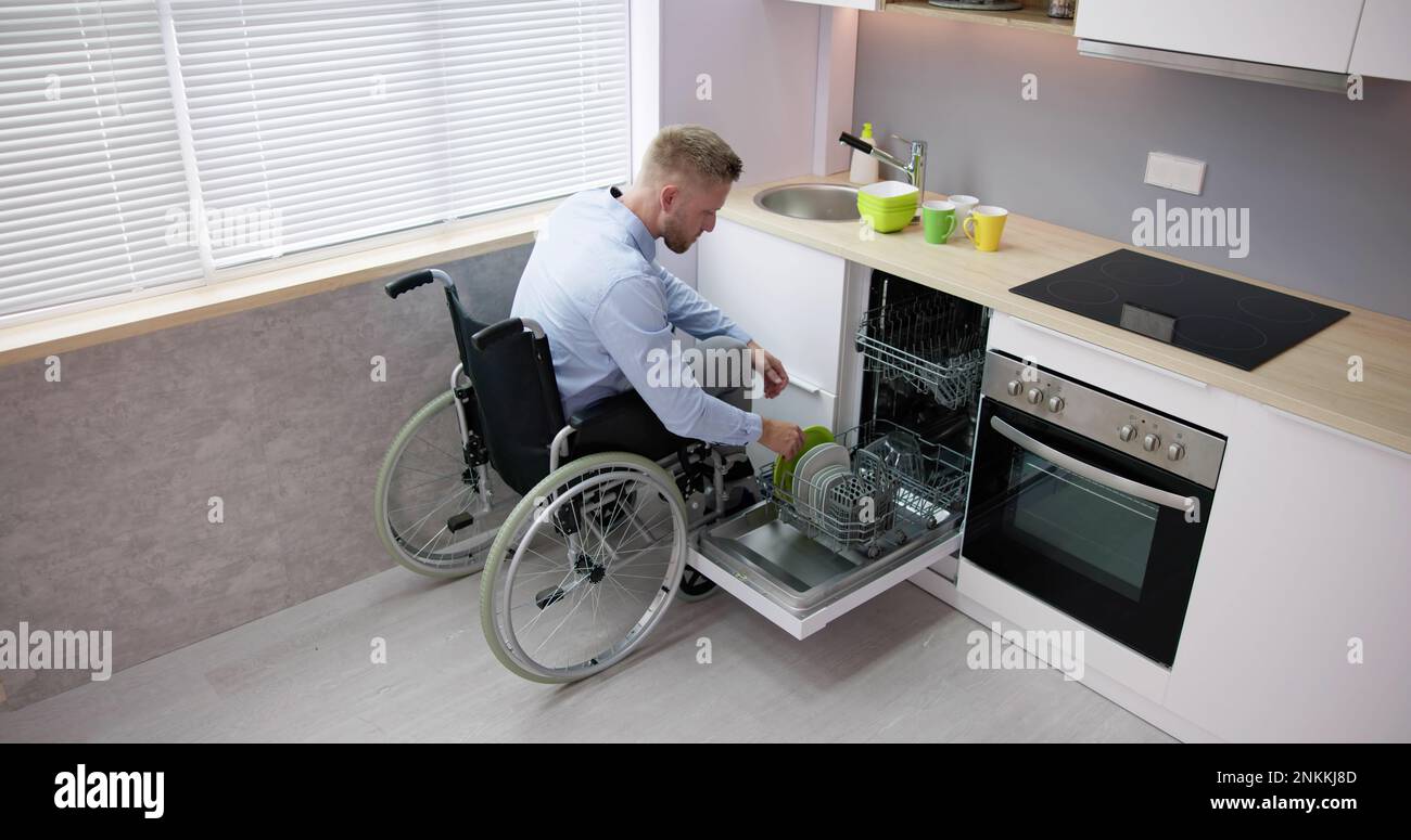 Person With Disability In Wheelchair Using Dishwasher In Kitchen Stock ...
