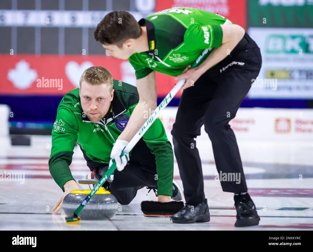 Team Saskatchewan skip Colton Flasch, left, makes a shot as second Kevin Marsh sweeps while playing Team Canada at the Tim Hortons Brier curling event in Lethbridge, Alberta, Monday, March 7, 2022