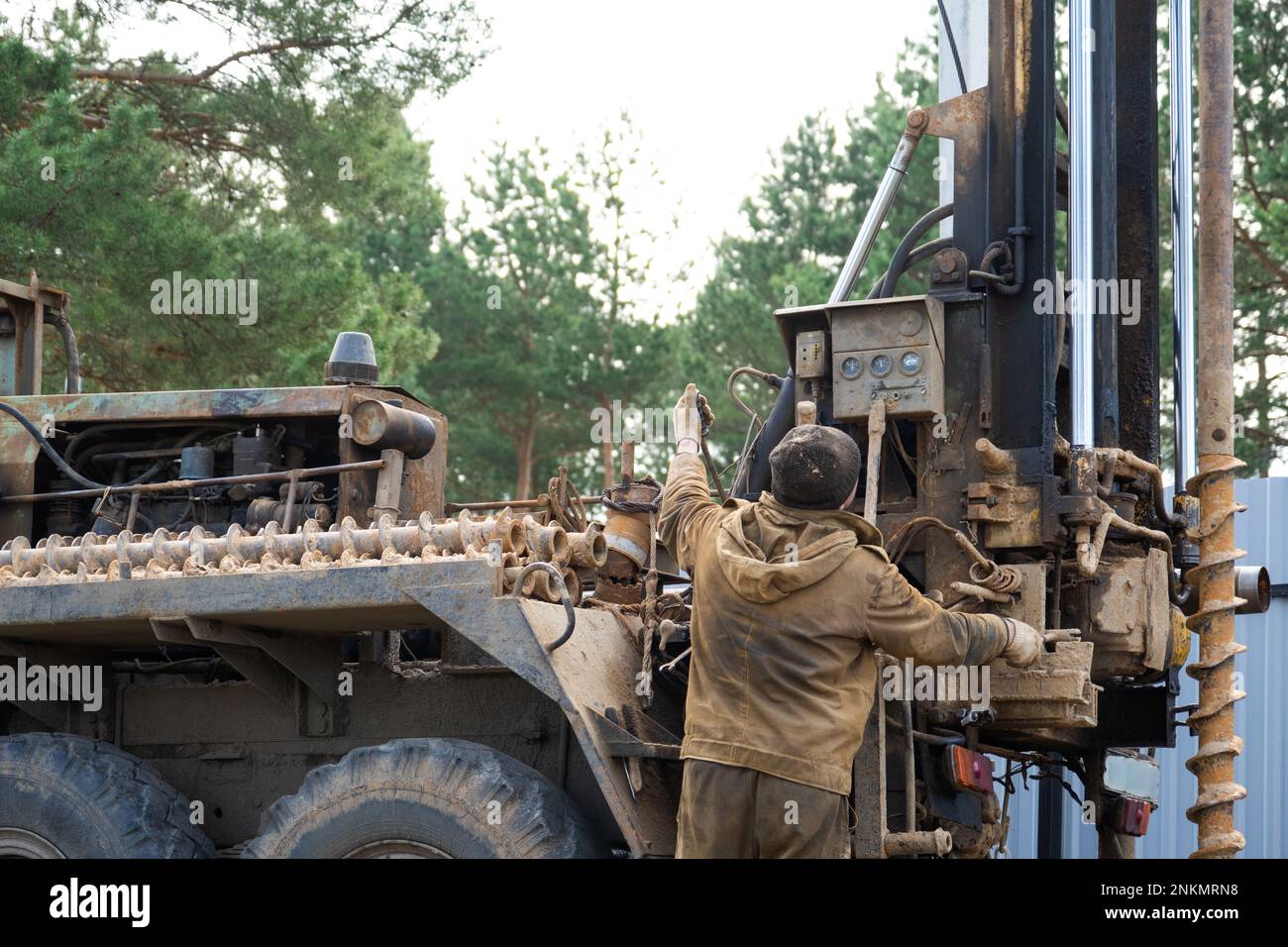 Team of workers with drilling rig on car are drilling artesian well for
