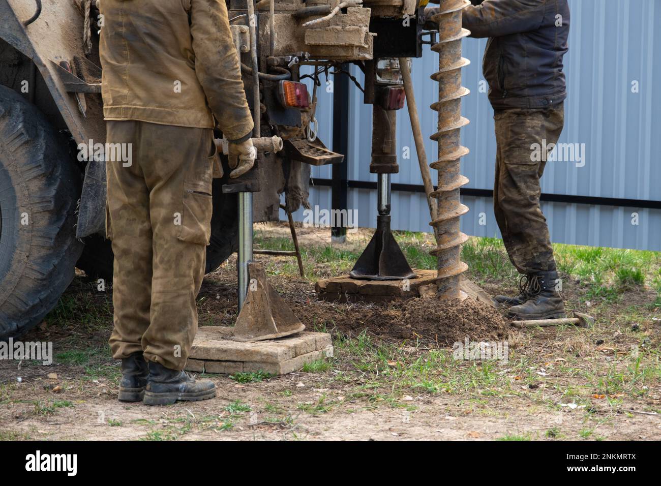 Team of workers with drilling rig on car are drilling artesian well for