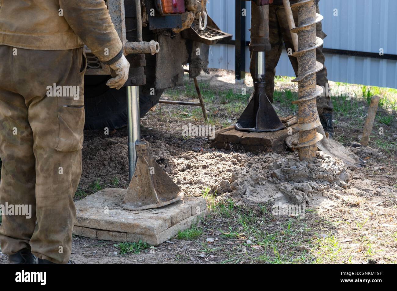 Team of workers with drilling rig on car are drilling artesian well for